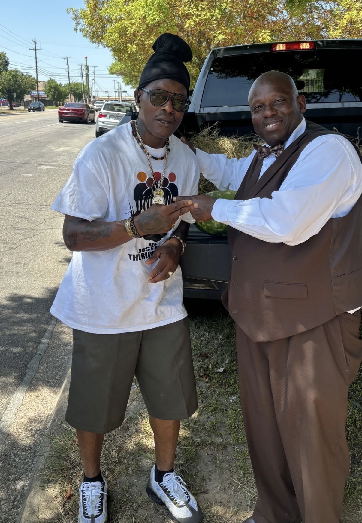 Two supporters greeting each other by the truck loaded with watermelon