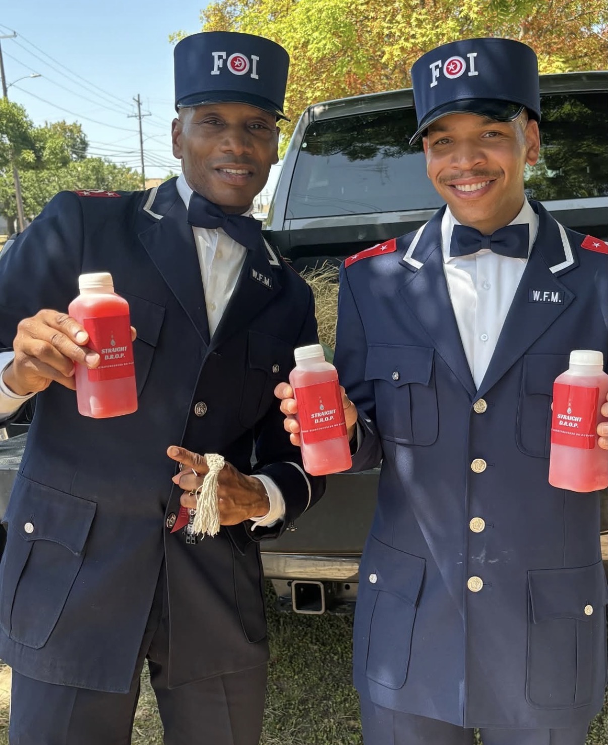 Two FOI members in uniform holding bottles of Straight D.R.O.P. watermelon juice